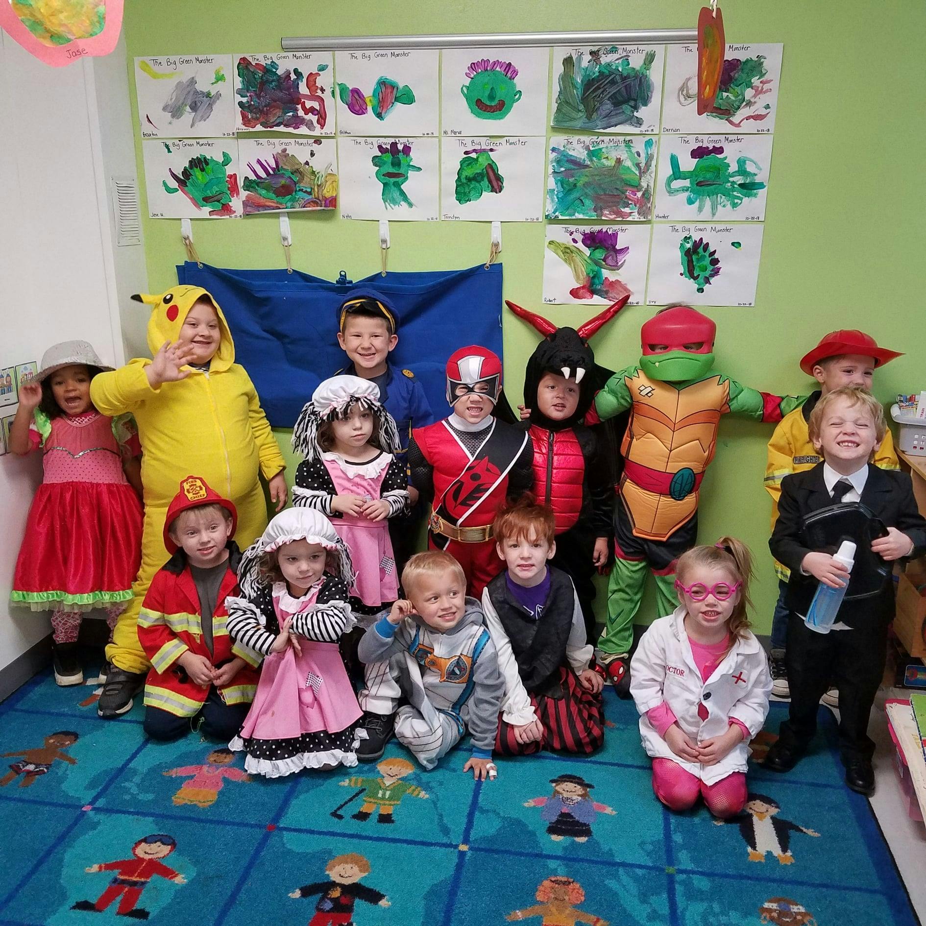Group of children in various costumes posing in a classroom