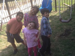 Four children standing in a yard near a swing set