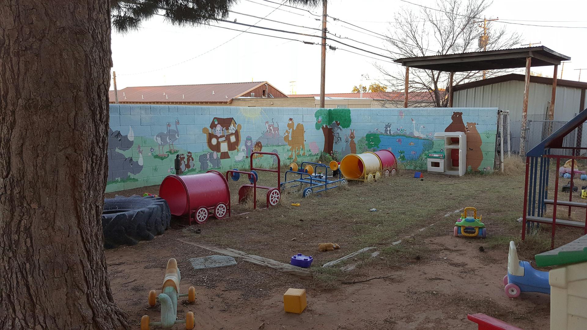 Outdoor play area with toys and a painted wall mural