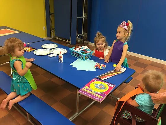Children at a blue table with craft supplies