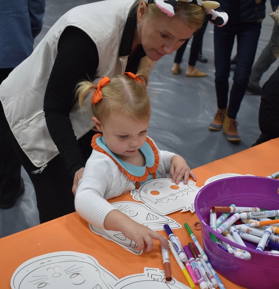 Adult and child coloring paper cutouts at a table