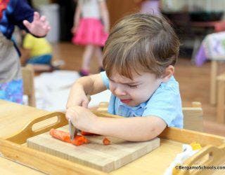 Child cutting a carrot on a wooden board