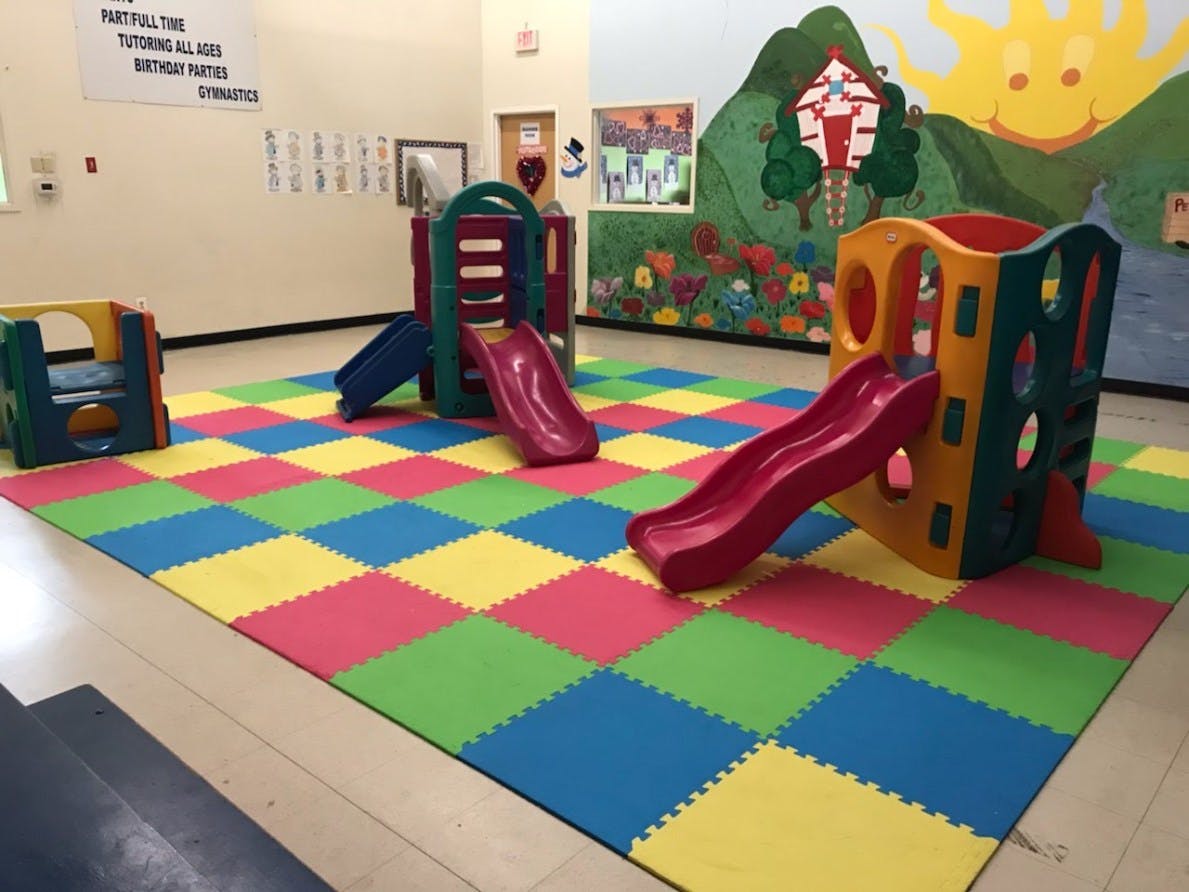 Indoor playground with colorful slides and play structures on a checkered mat