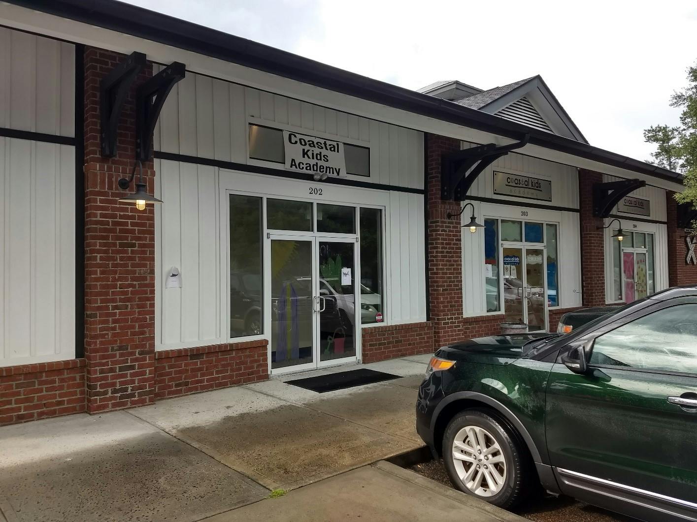 Exterior of Coastal Kids Academy with a dark green SUV parked in front