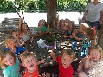 Children sitting around a picnic table outdoors