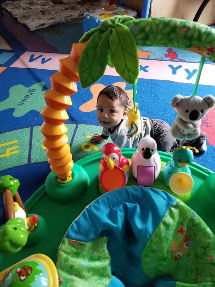 Child crawling on a playmat with toys