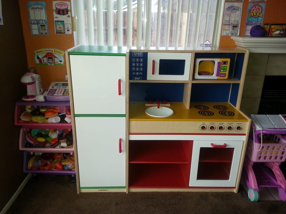 Child's play kitchen with refrigerator, microwave, sink, and stove
