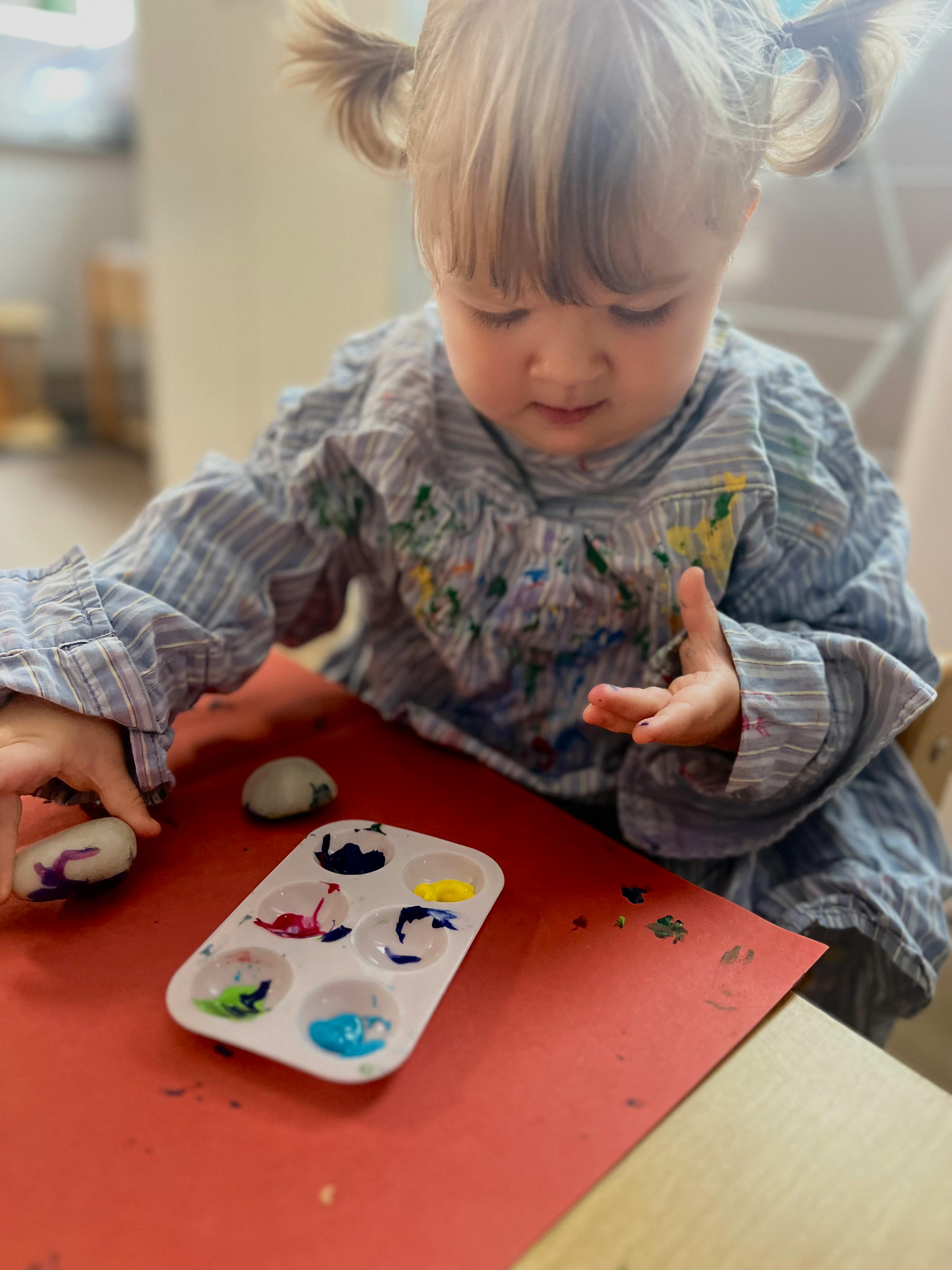 Child painting rocks with a paint palette
