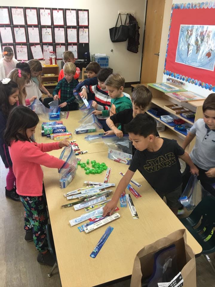 Children sorting items into plastic bags at a table