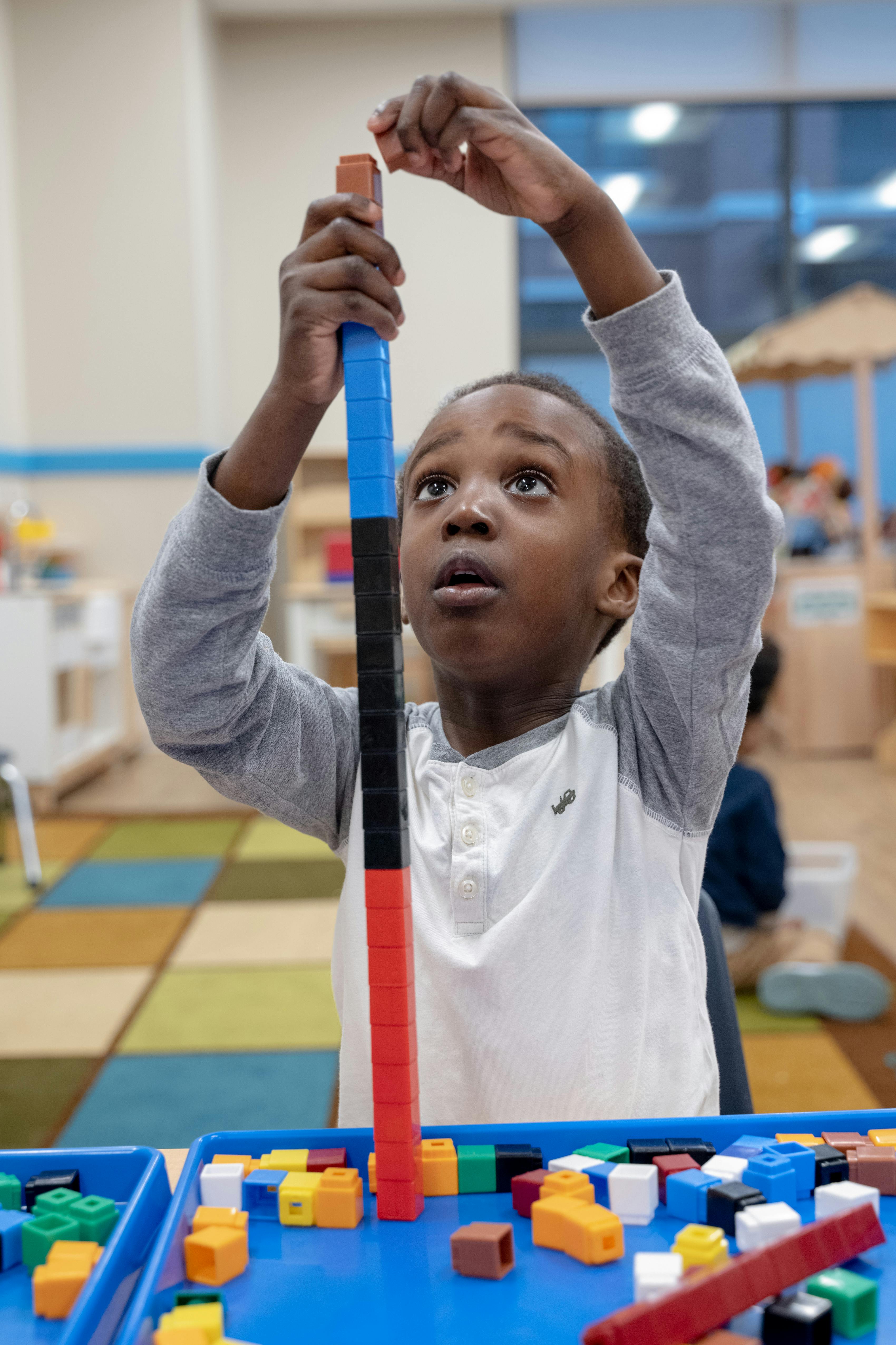 Child building a tall structure with colorful interlocking blocks