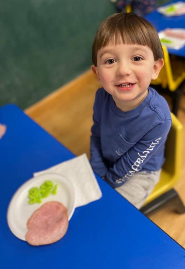 Child sitting at a blue table with a plate of food
