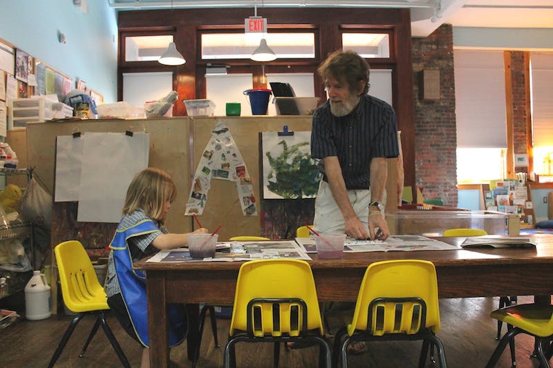Adult and child working on art projects at a table in a classroom