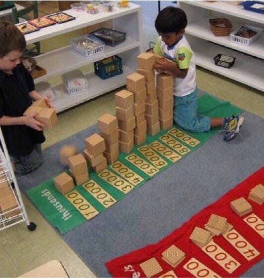 Two children building towers with wooden blocks on numbered mats