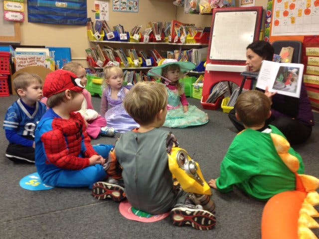 Adult reading a book to children in a classroom
