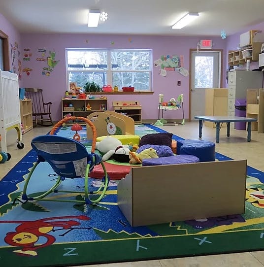 Playroom with a colorful rug, baby bouncer, and various toys