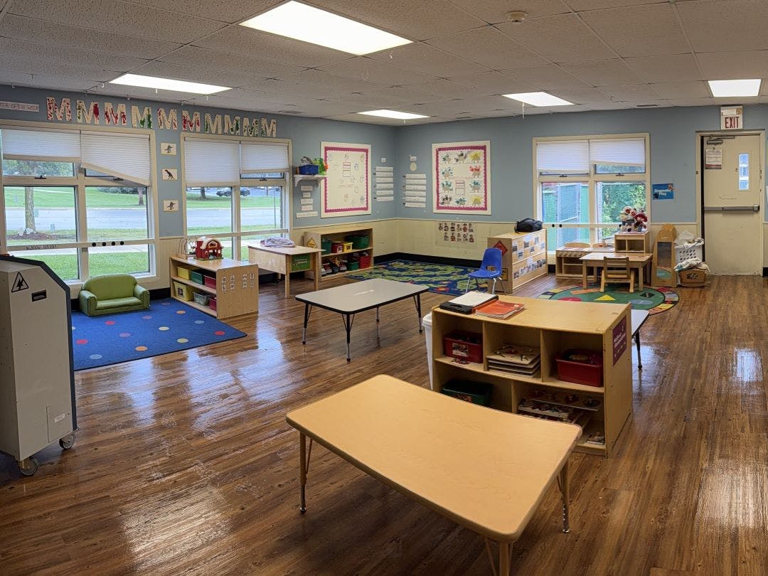 An empty early childhood classroom with multiple tables and shelves