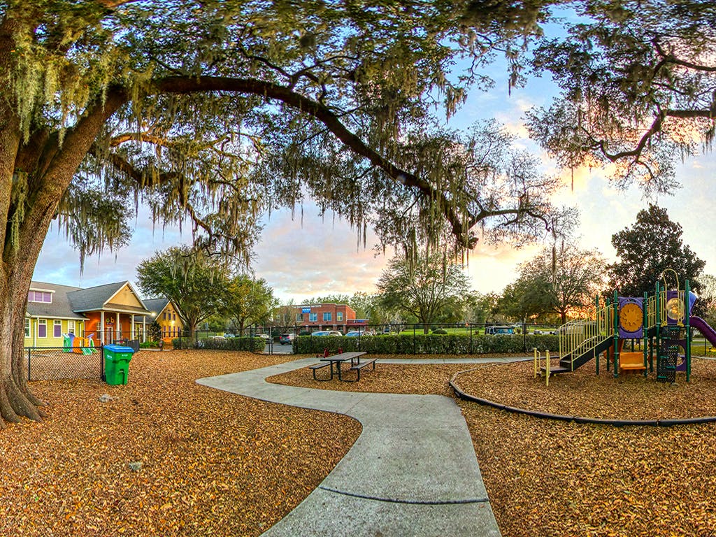 A playground with wood chips under a large tree with Spanish moss