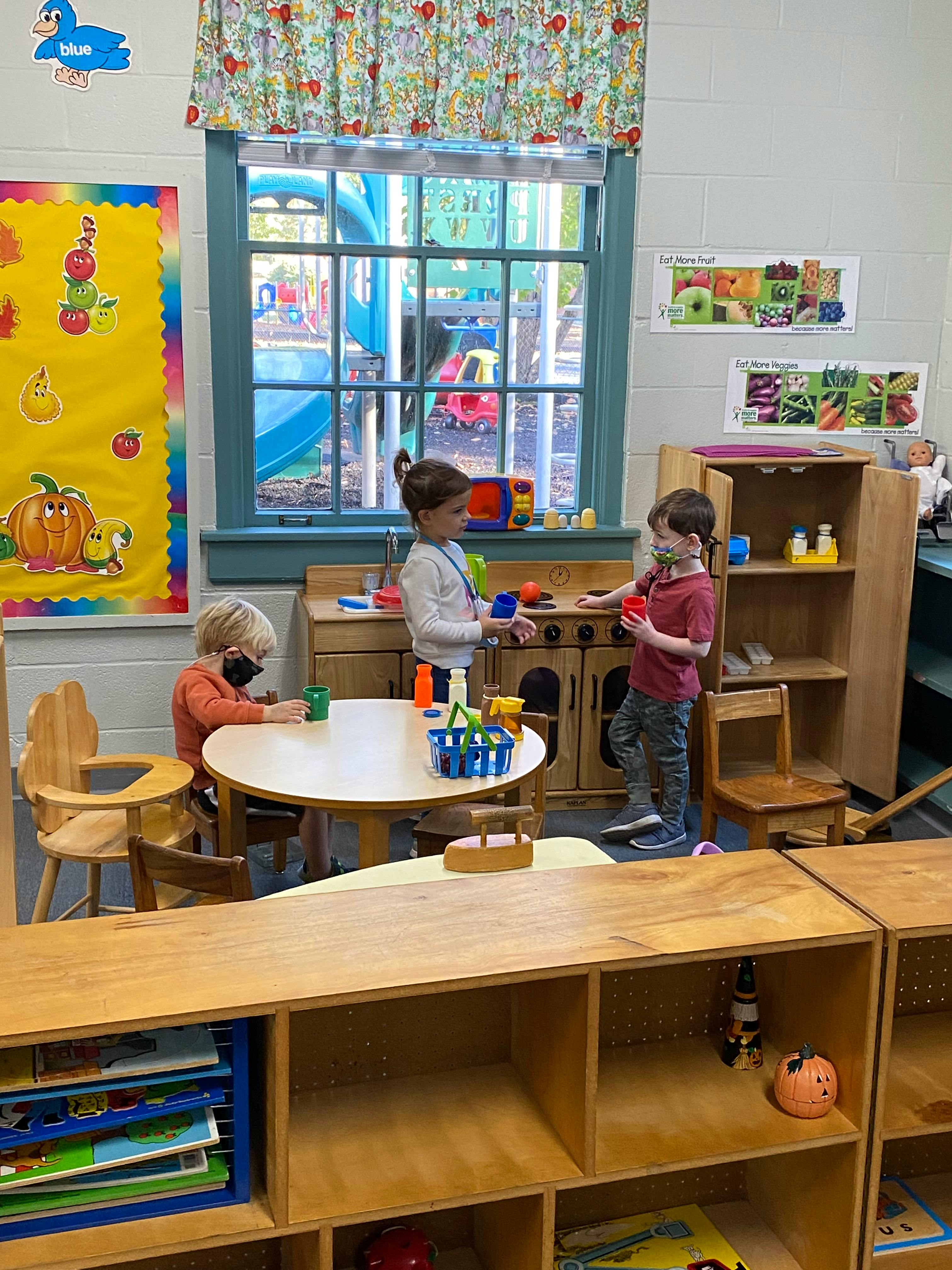 Three children playing in a classroom