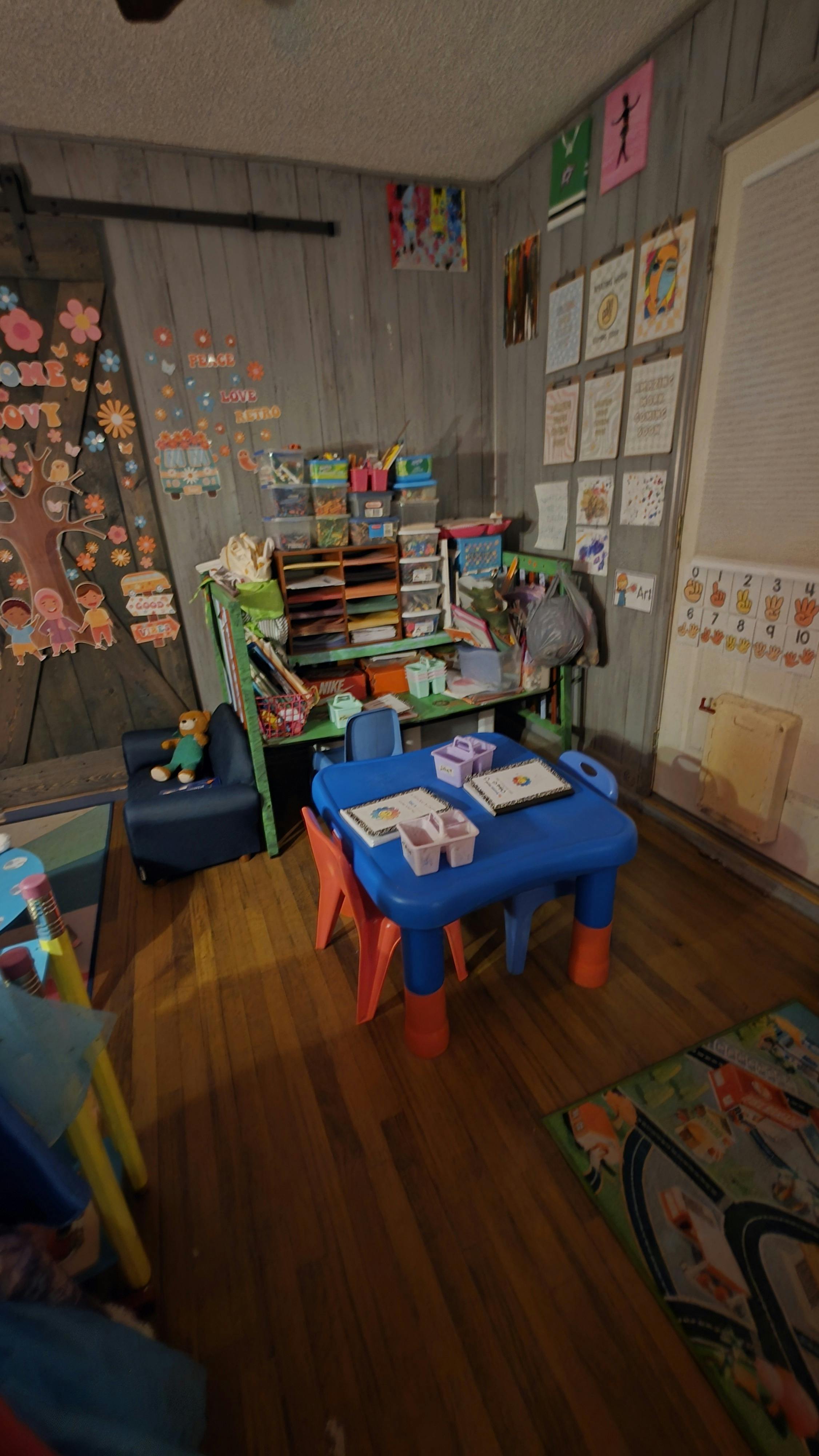 child's play area with a blue table, chairs, and shelves filled with supplies