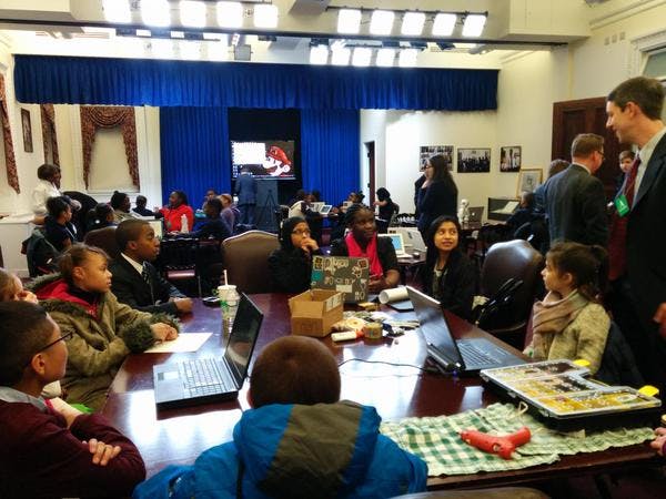 People and children gathered around a large table with laptops