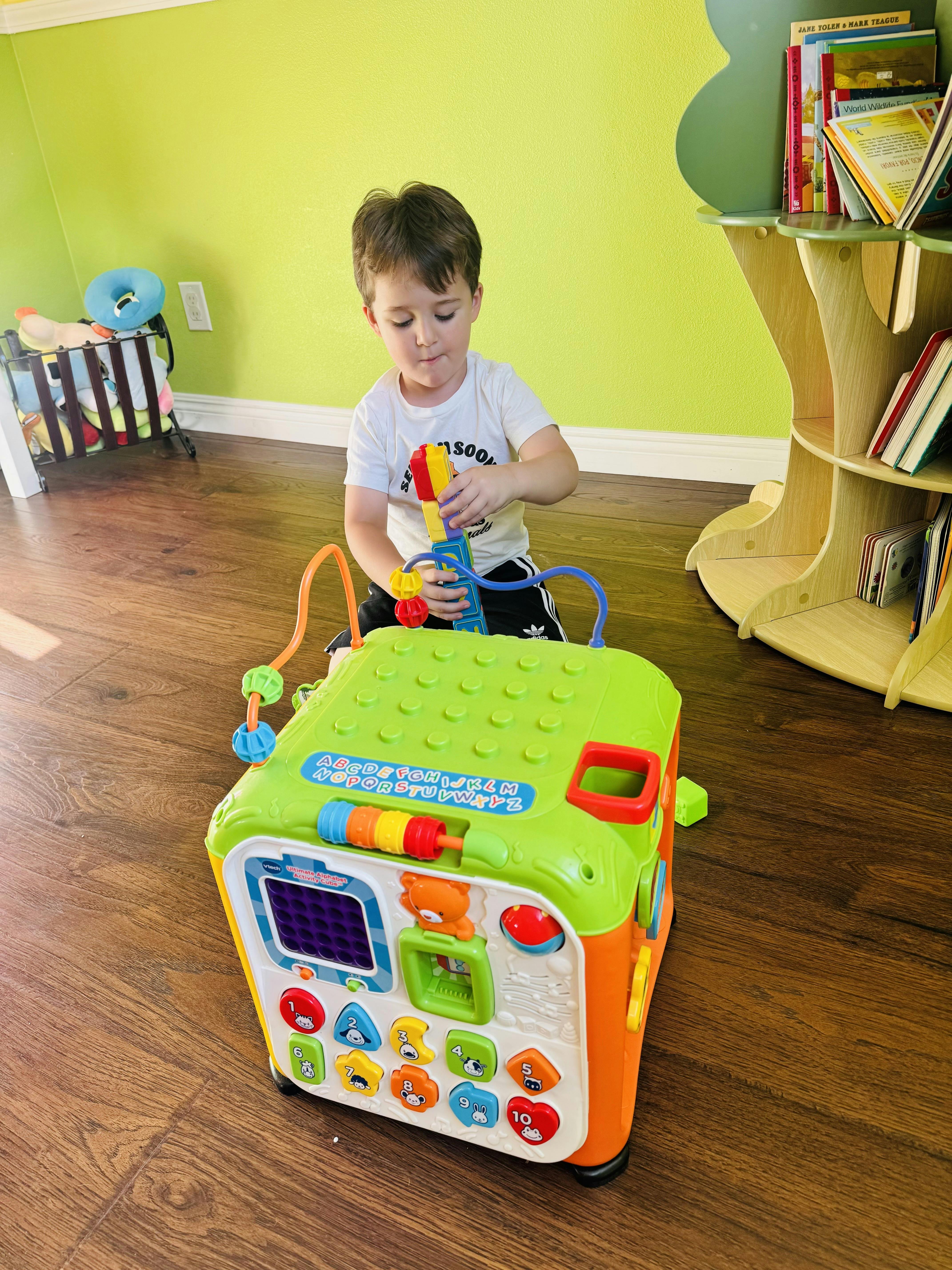 Child playing with a colorful activity cube in a room