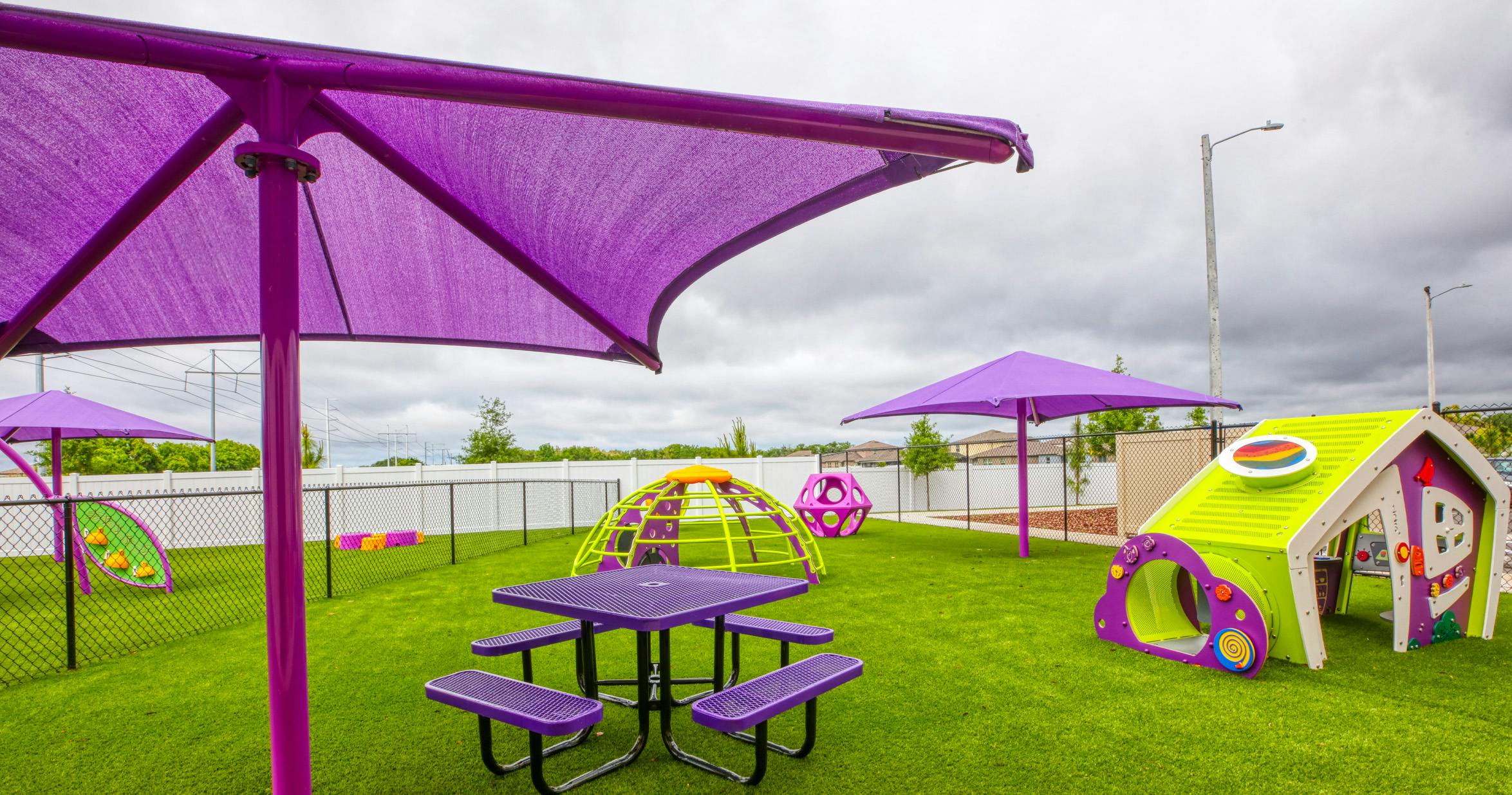 Playground with purple sun shades, a purple picnic table, and colorful play structures