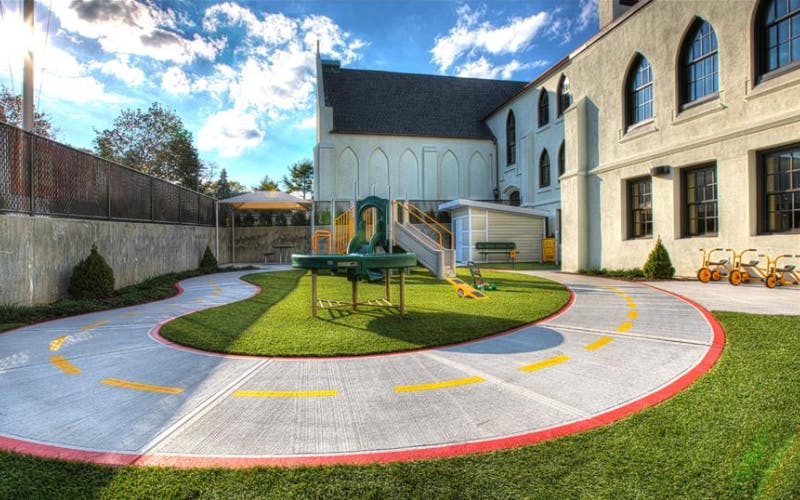 Outdoor playground area with a winding path, artificial turf, and play equipment