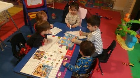 Children sitting at a table with papers and drawing