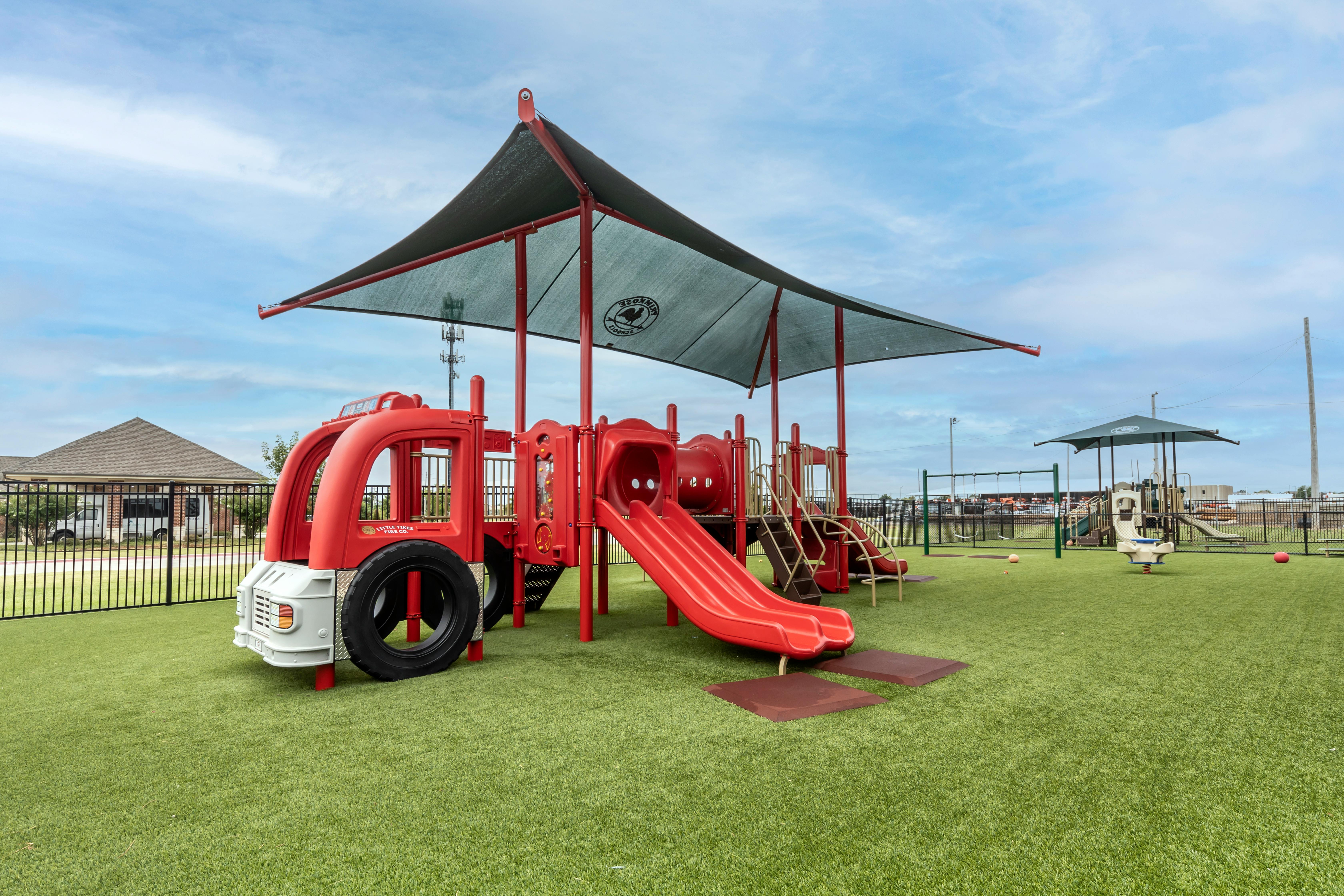A red fire truck-themed playground slide and climbing structure