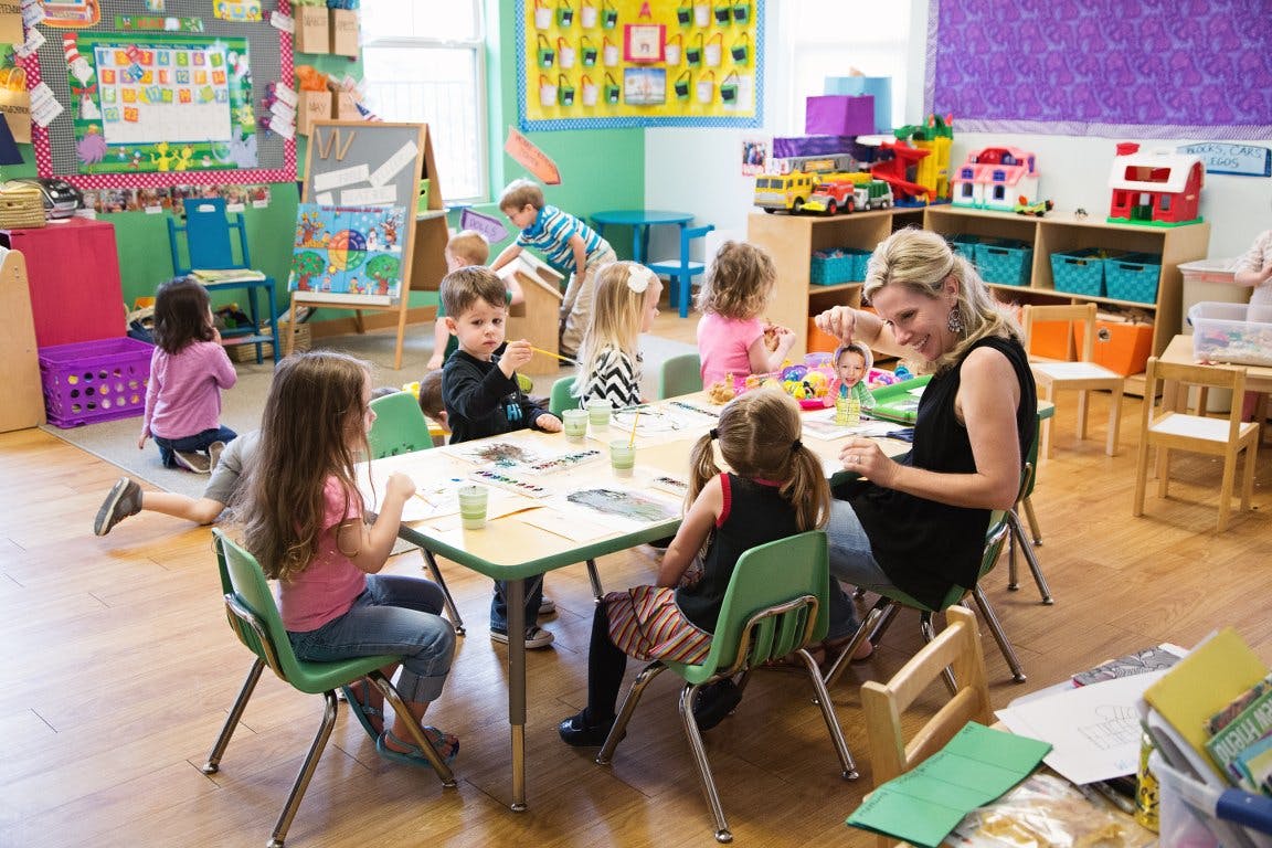 Adult and children sitting at tables in a classroom