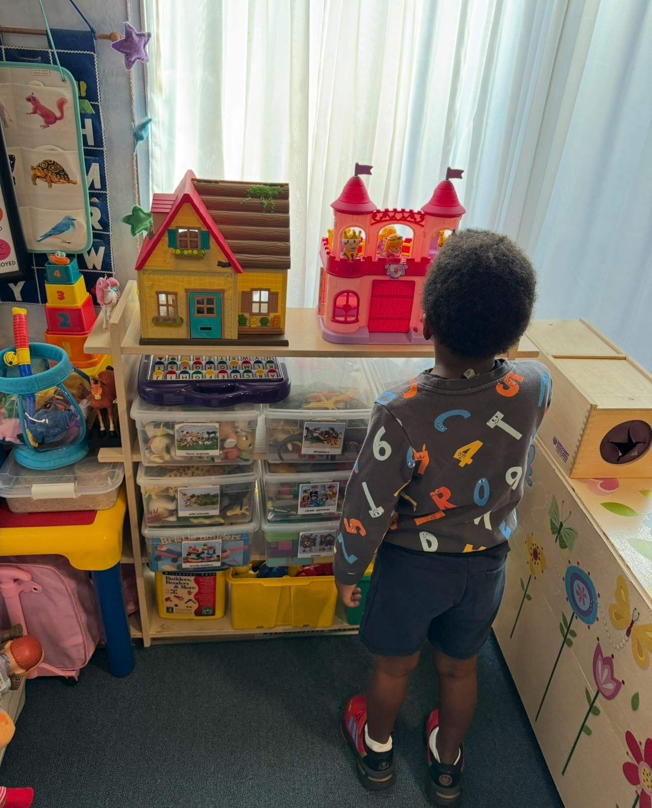 Child standing in front of a toy house and castle