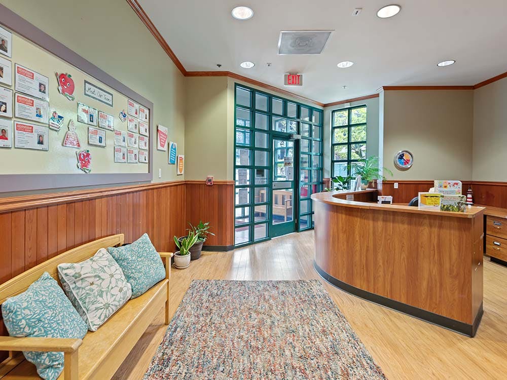 Lobby area with a wooden bench, a large rug, a front desk, and a glass door