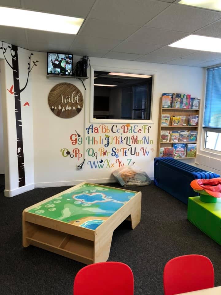 Playroom with alphabet wall decals, a play table, and bookshelves