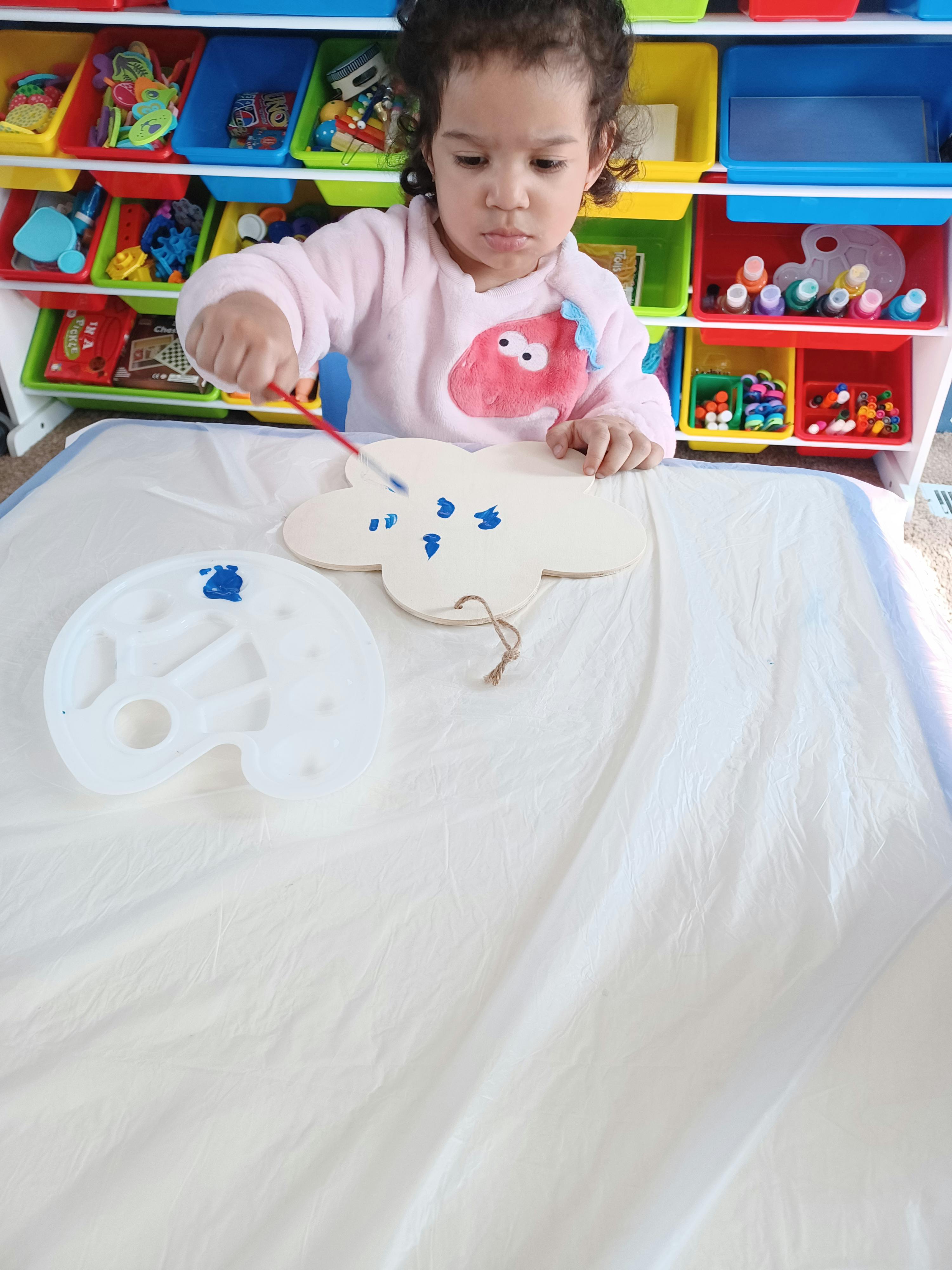 Child painting a cloud shape with blue paint