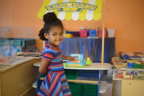Child standing next to a toy lemonade stand