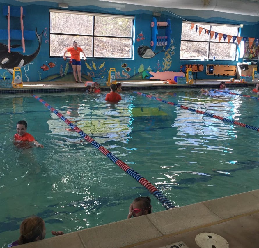 People in a swimming pool with a person standing on the side