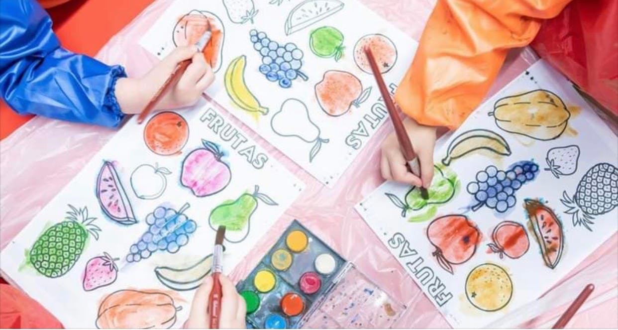Two children painting fruit pictures with watercolors