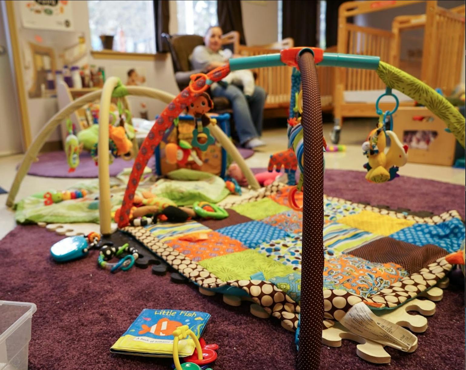 Play mat with toys and a person sitting in the background