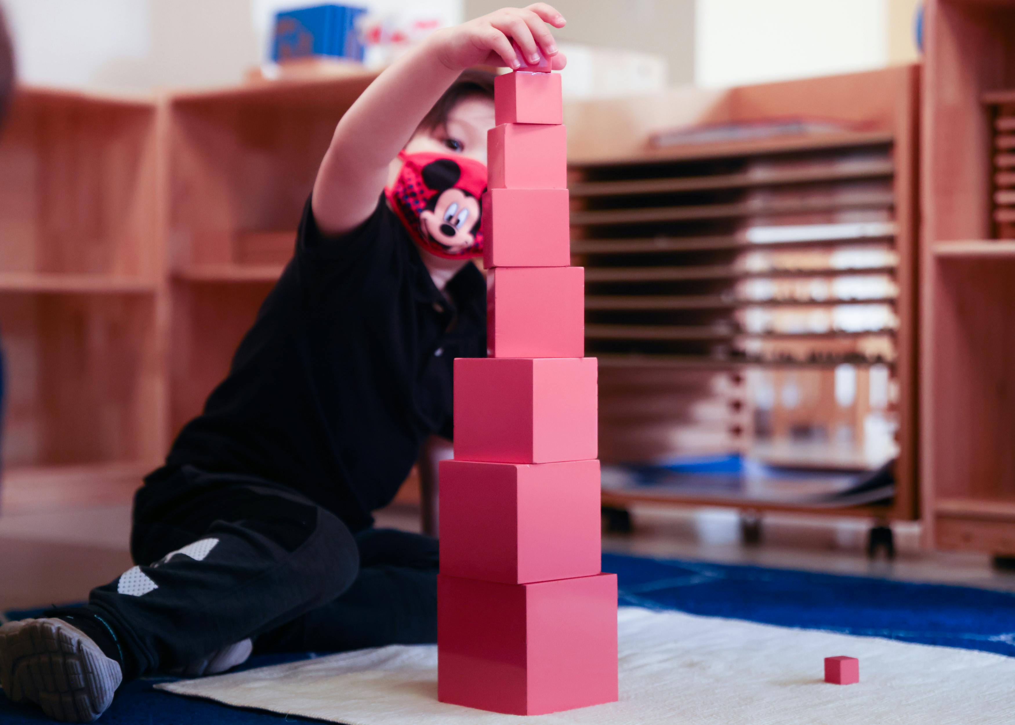 Child building a tower with pink blocks