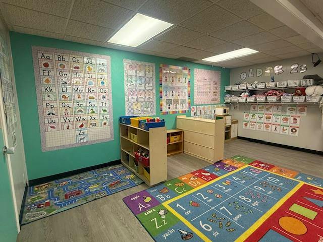 Classroom interior with educational wall posters, toy storage, and rugs