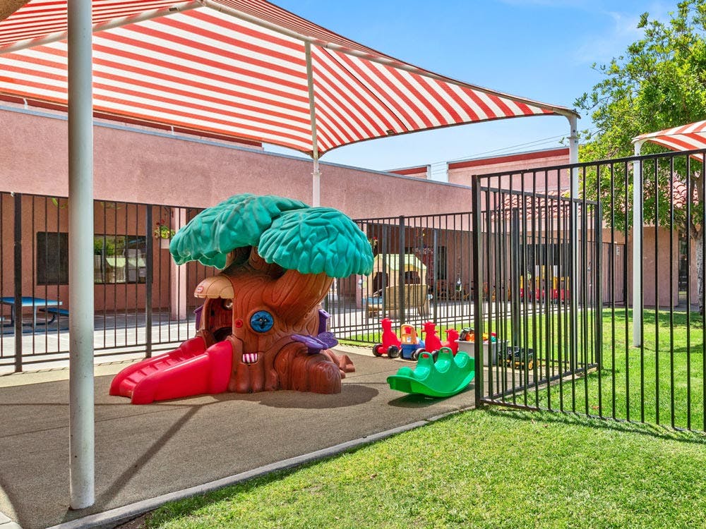 Playground with a treehouse slide and a red and white striped awning