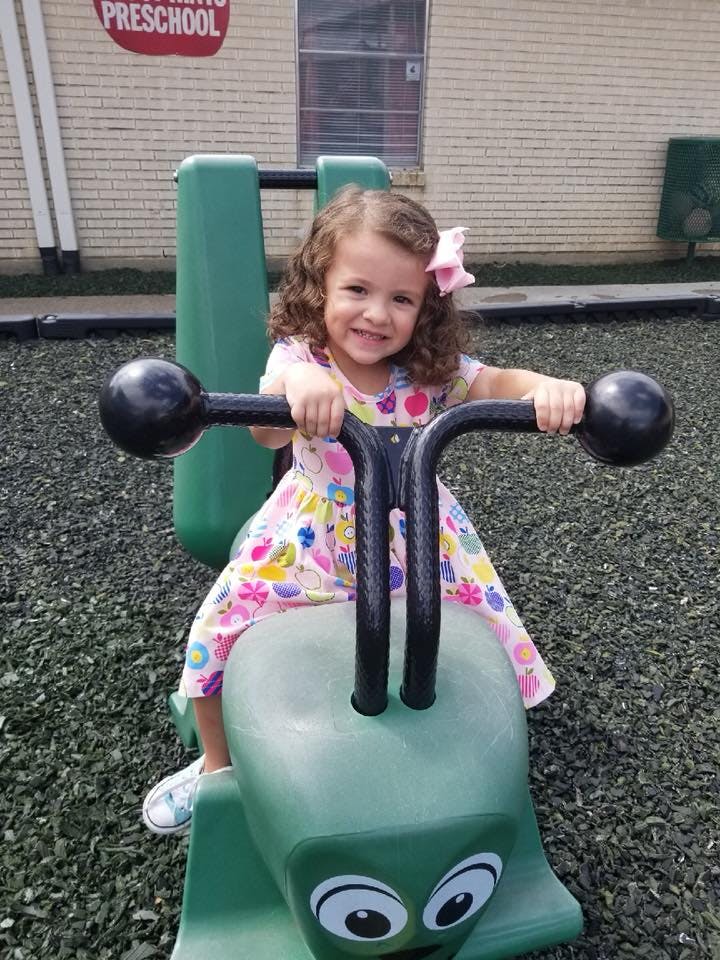Child on a green spring rider toy at a playground