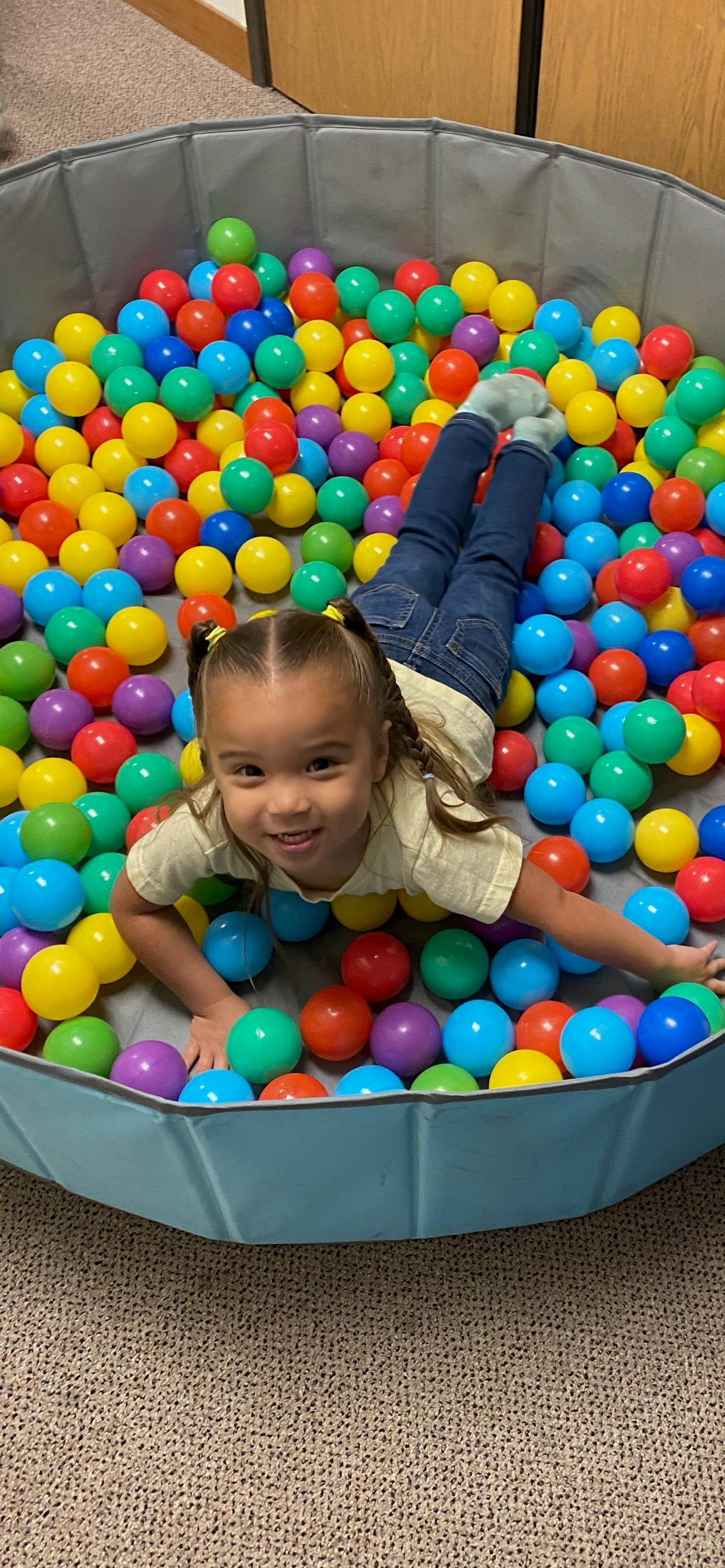 Child lying in a ball pit