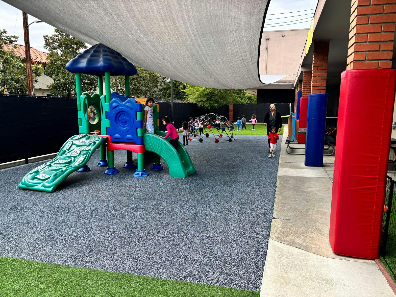 Children playing on a colorful playground with a slide and climbing dome