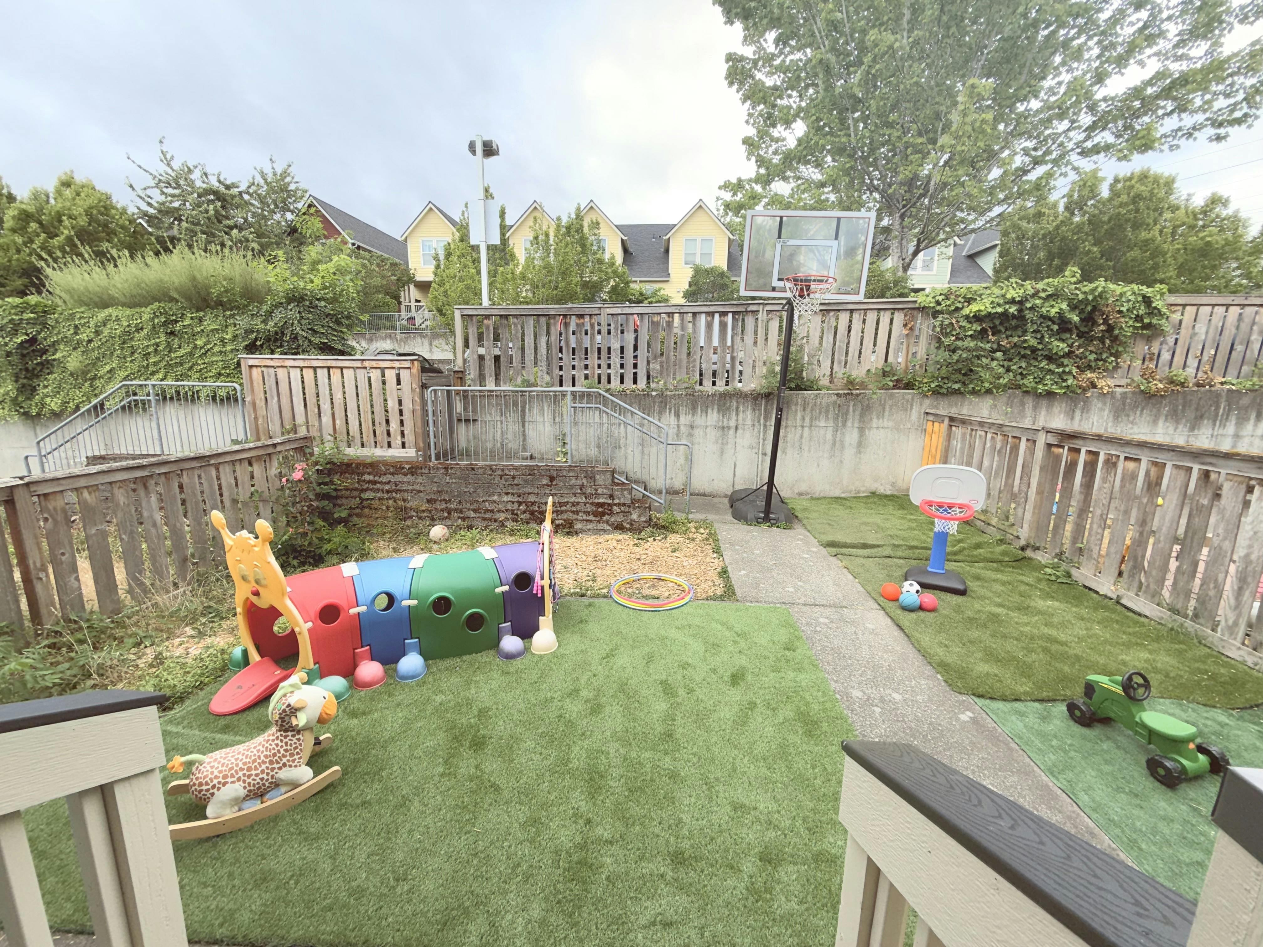 Backyard with a play tunnel, rocking horse, and basketball hoops