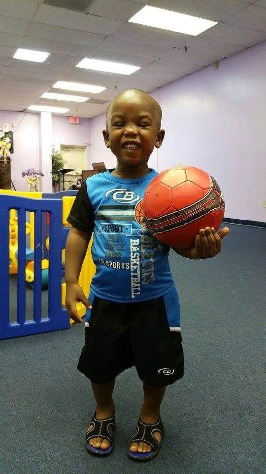 Child holding a red and black ball
