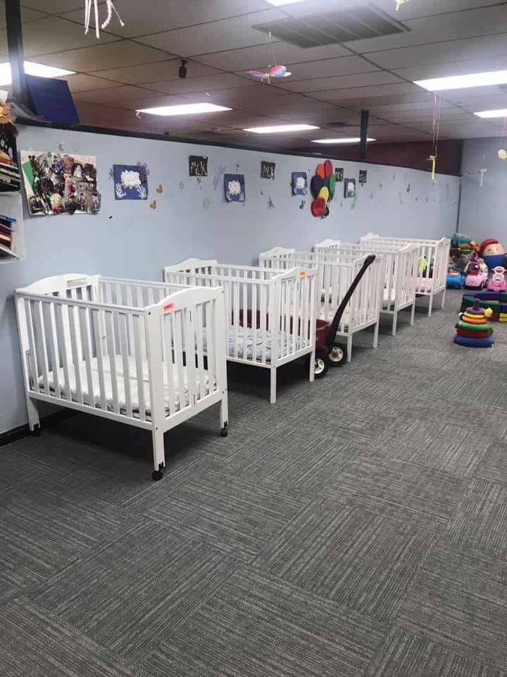 Multiple white cribs in a room with carpeted floor