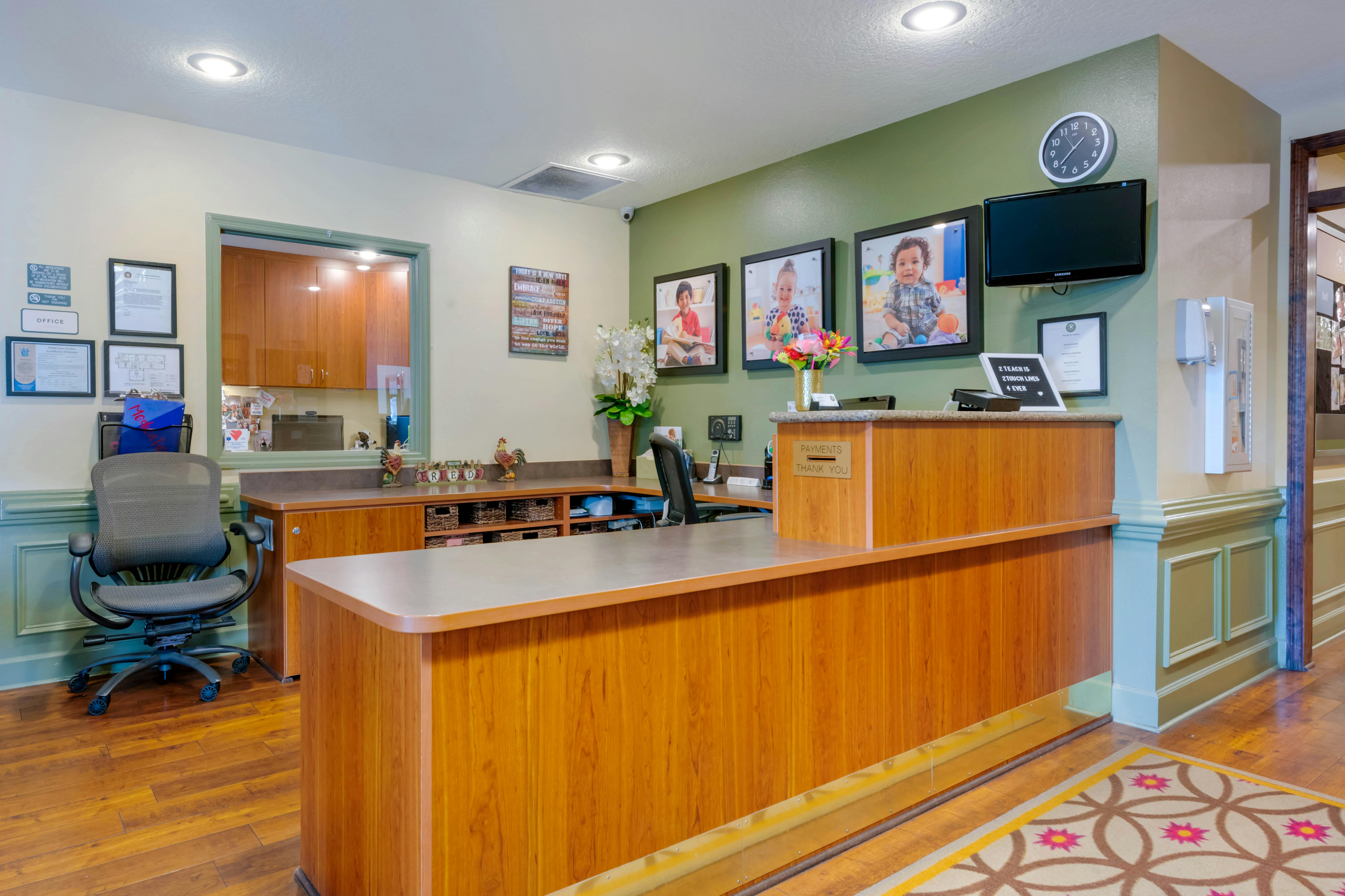 Reception desk with office chair, monitor, and framed pictures of children