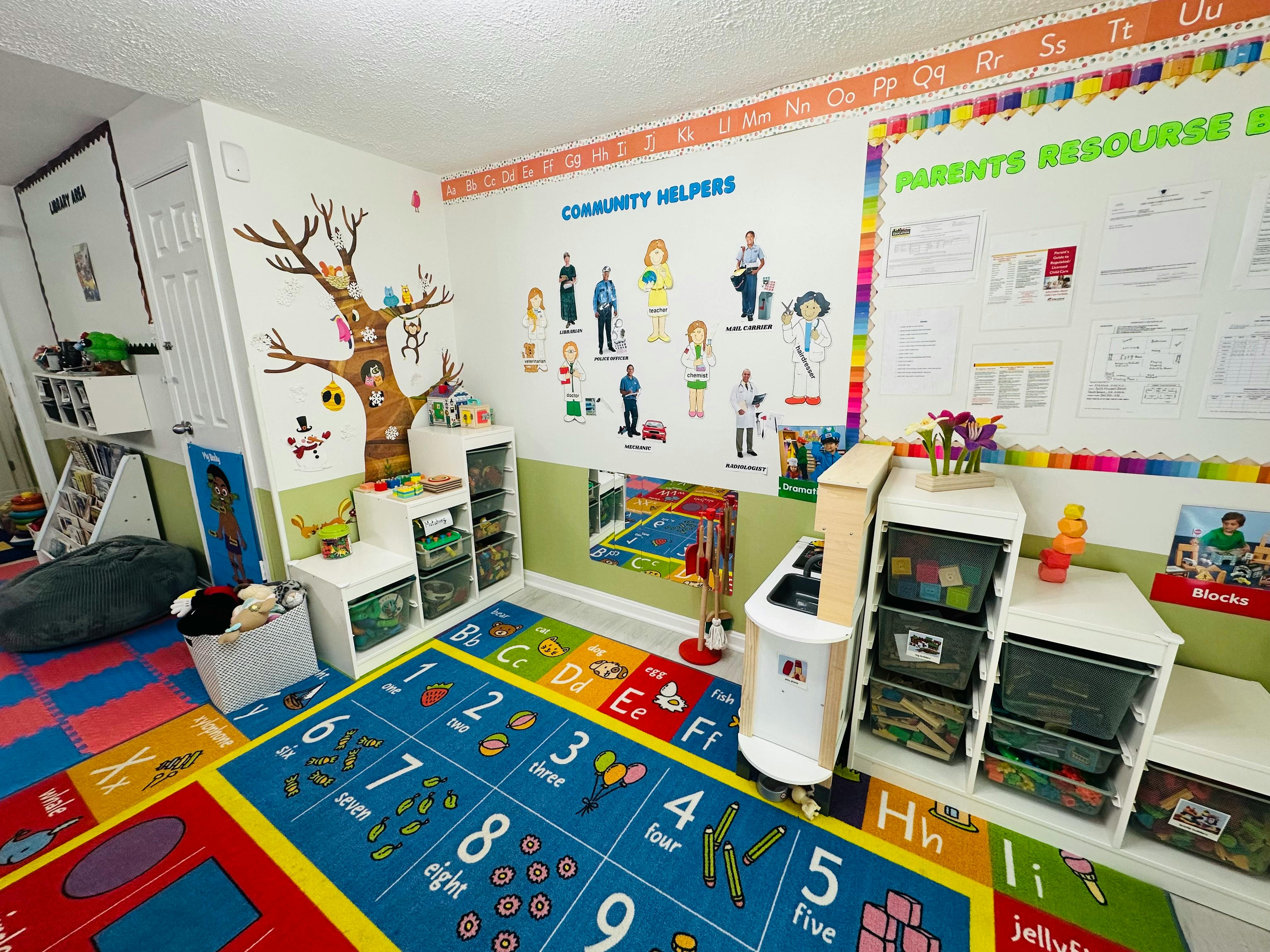 Classroom with an alphabet rug, labeled community helper cutouts, and cubbies with toys
