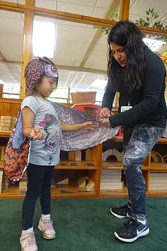 Adult helping child put on a costume